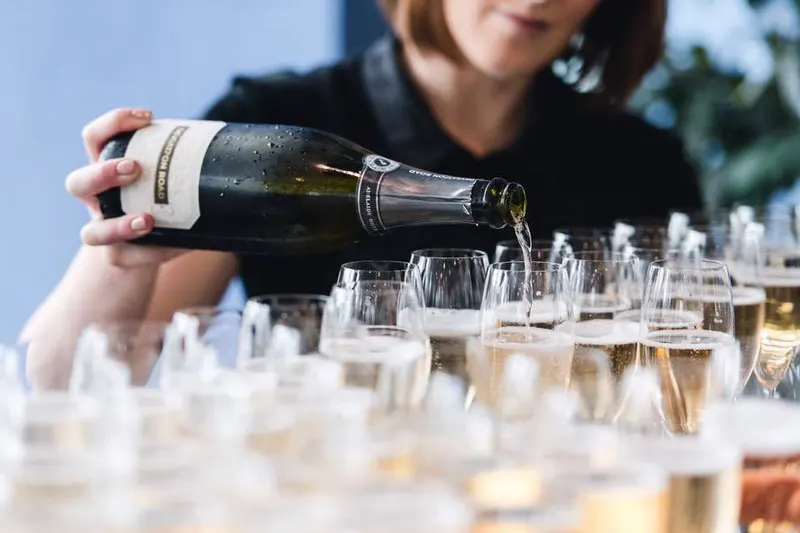 Staff member at Deviation Road pouring sparkling wine into glasses