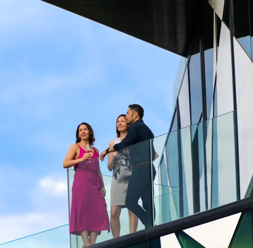 Three guests drinking wine on a balcony at d’Arenberg Cube