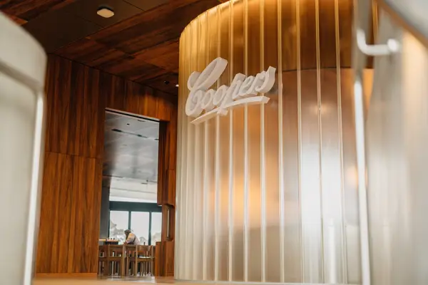 Coopers branded entrance inside a modern Australian restaurant with timber panelling and frosted glass feature wall.